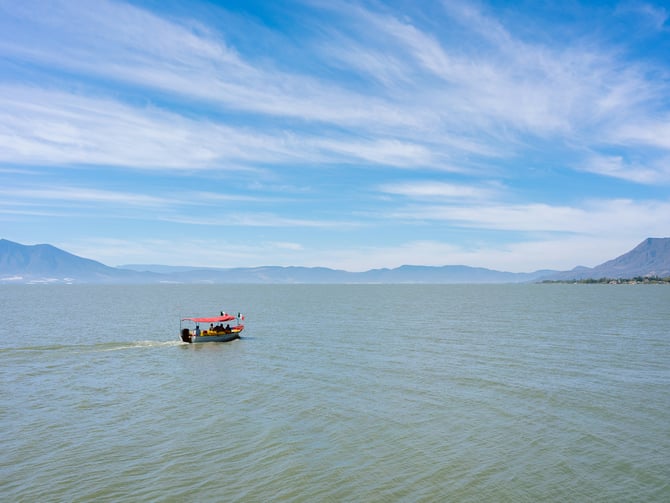 Red boat on Cajititlán lake with mountains in background